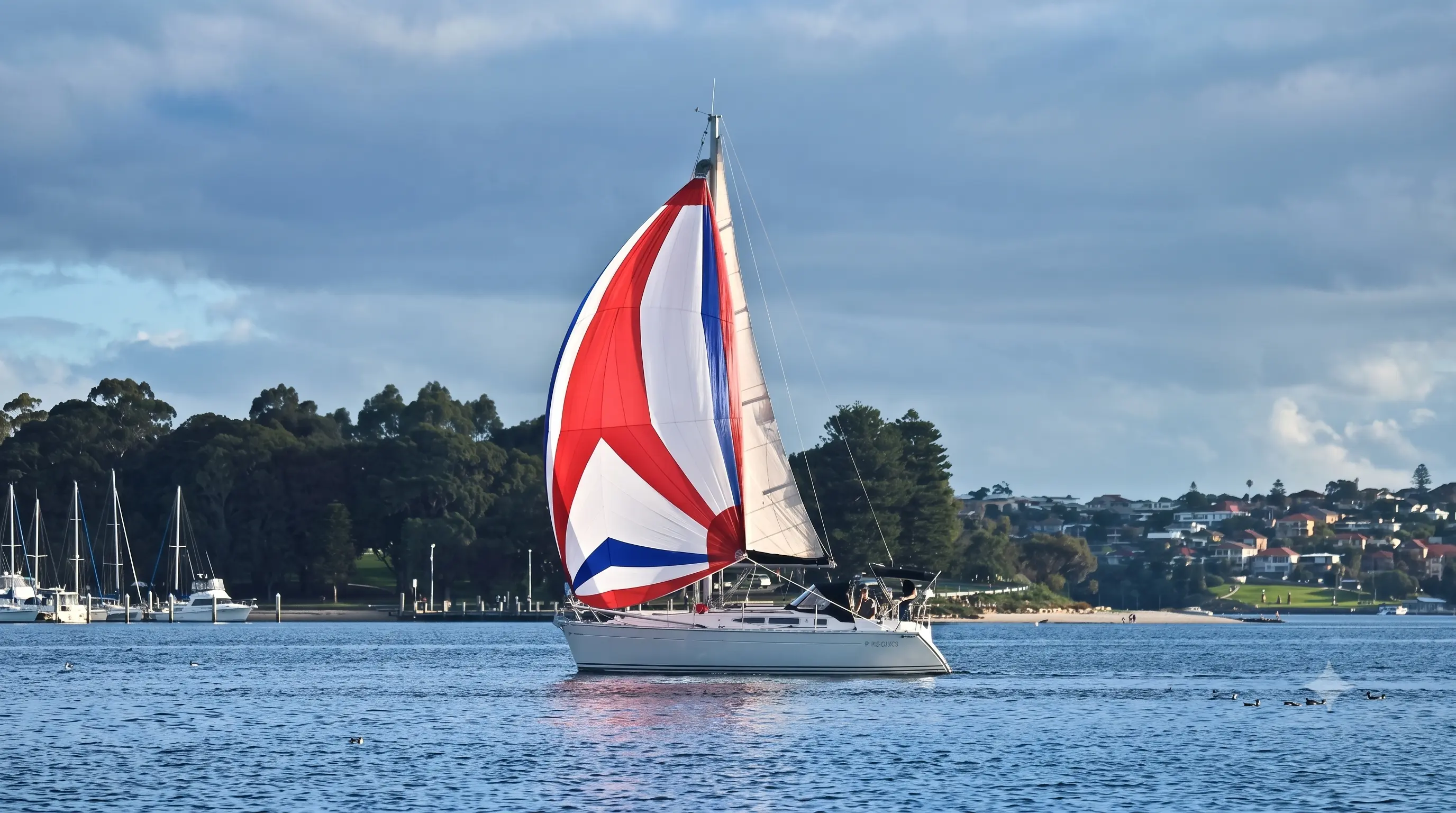 Red, white and blue spinnaker flying over sheltered water