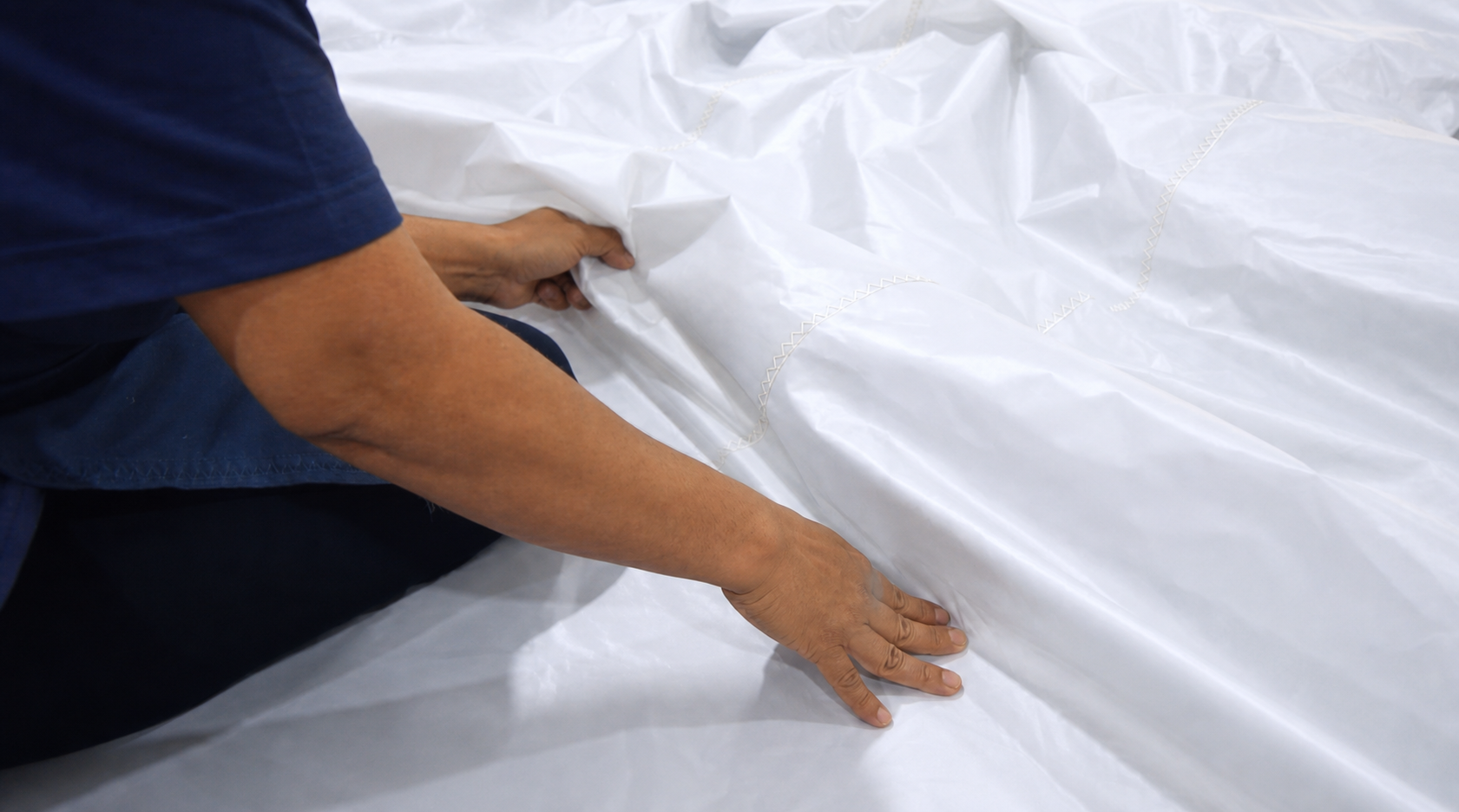 Sailmaker checking finished sailcloth by hand