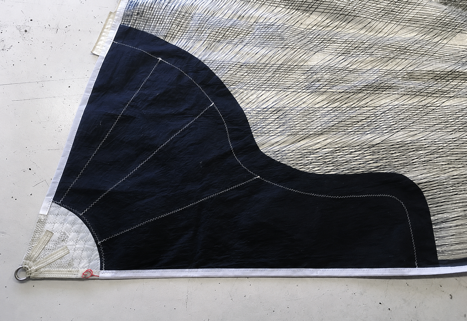 Reinforced sail corner with load-spreading patch and ring