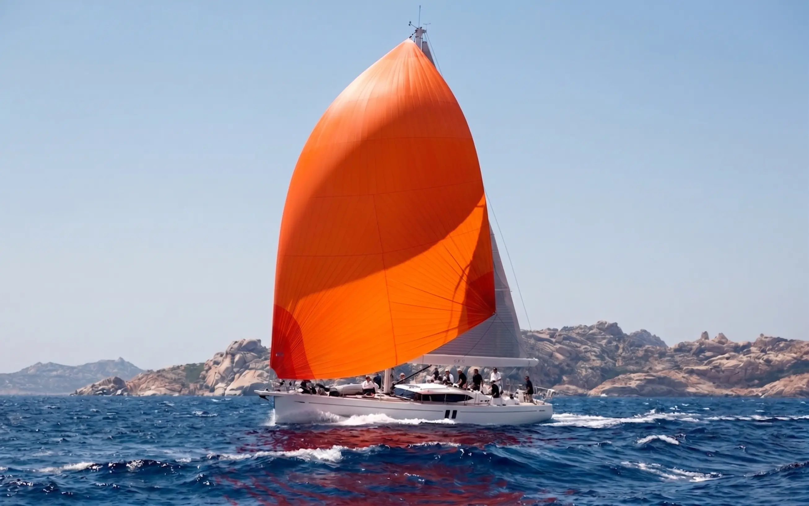 Orange gennaker flying from a yacht in open water